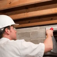 Termite inspection technician checking a basement wall and framing for termite activity in Toledo, OH